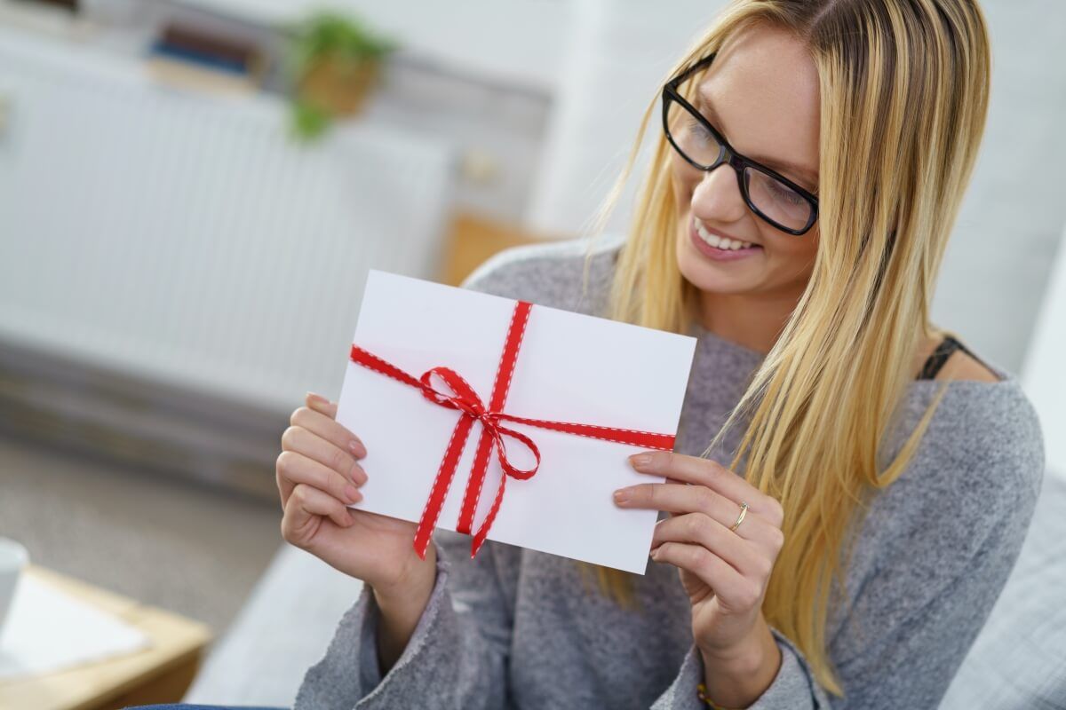 Frau packt Geschenkgutschein für Massage aus